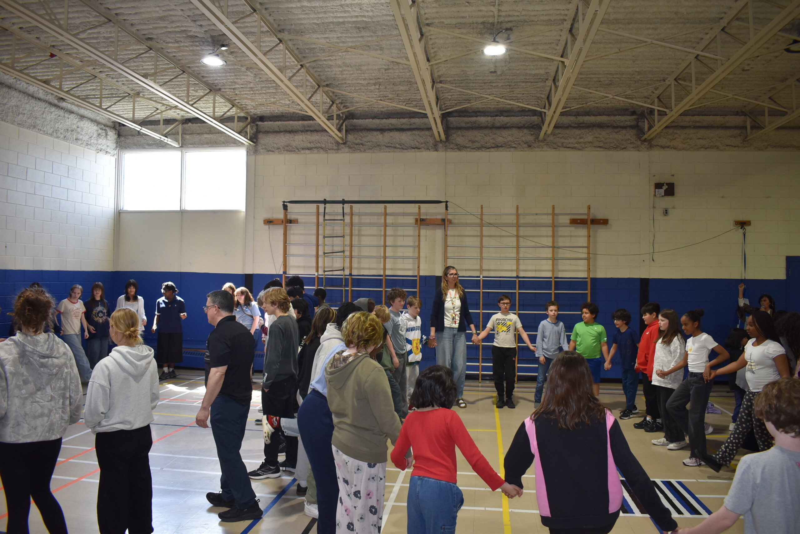 Students holding hands and dancing in the gym.