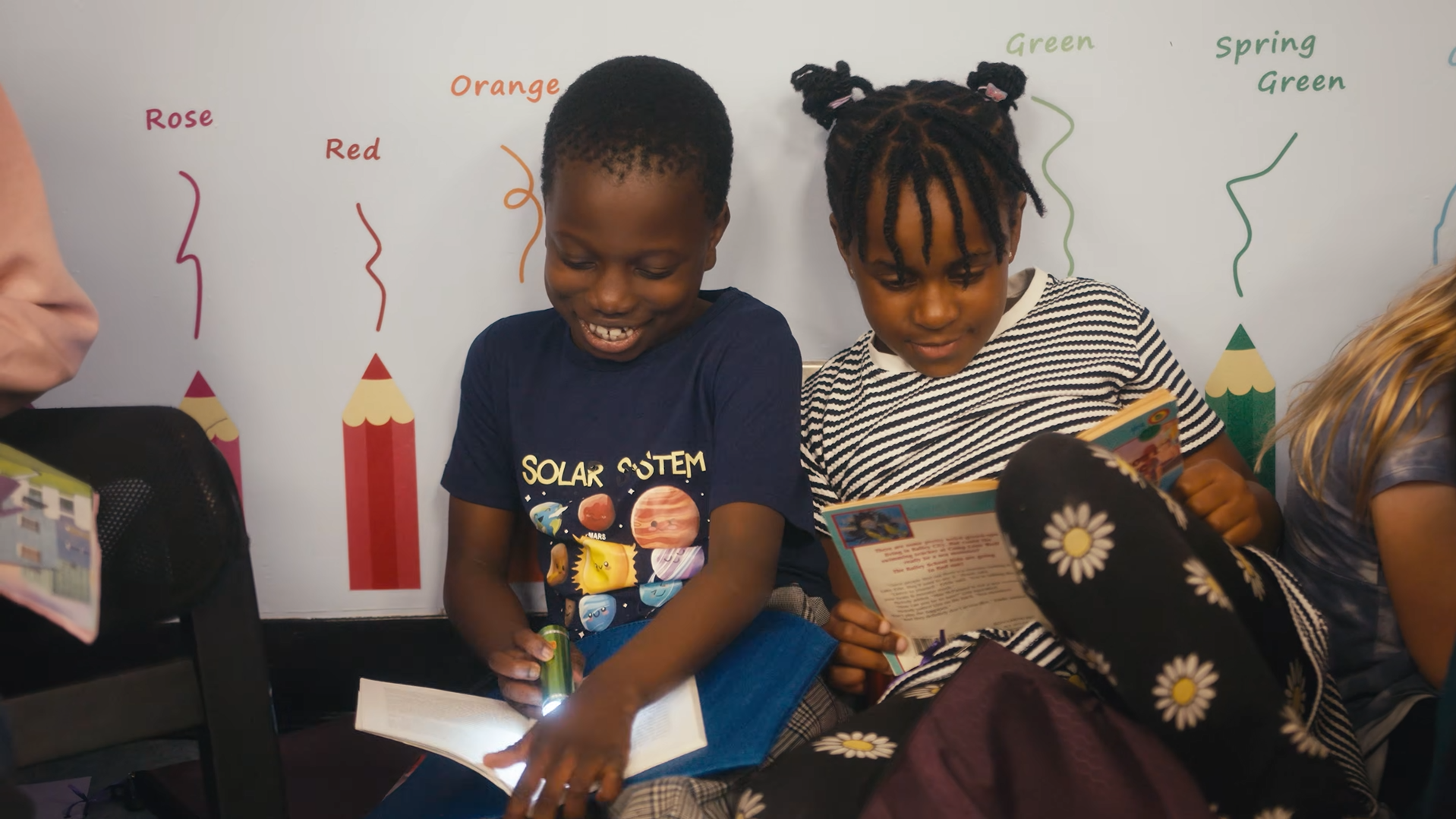 Two elementary students sitting down reading.