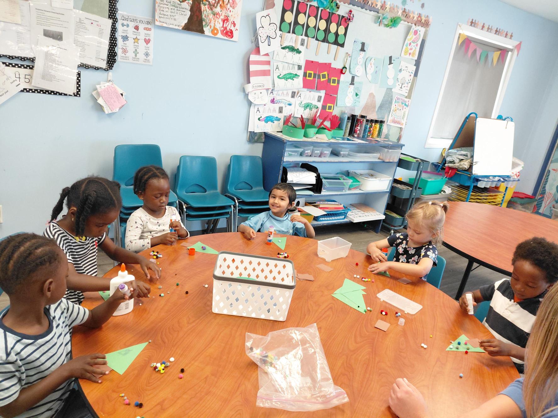 Daycare students doing crafts around a table.