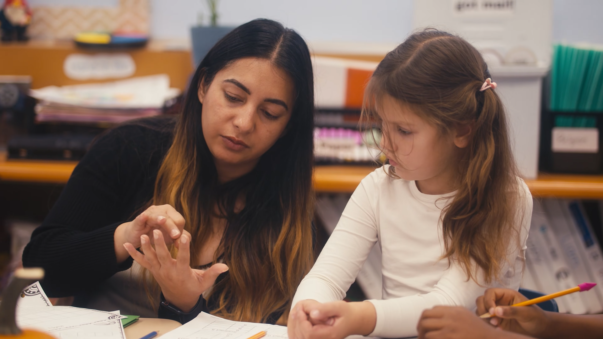 Teacher showing elementary student how to count.