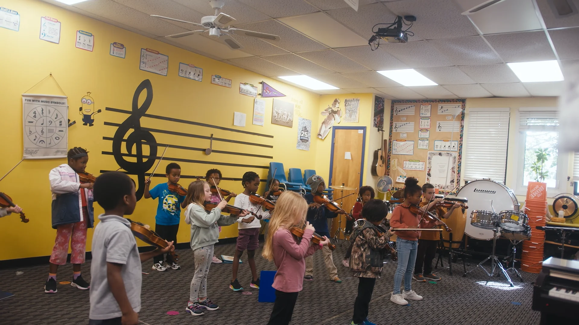 Students playing violin in a small music room.